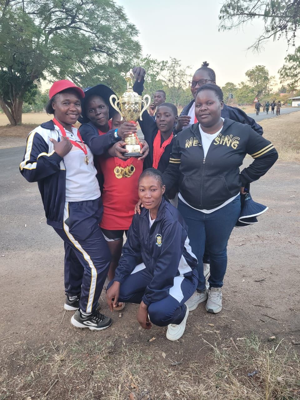 Twin One Academy students and staff celebrating a sports trophy near a road