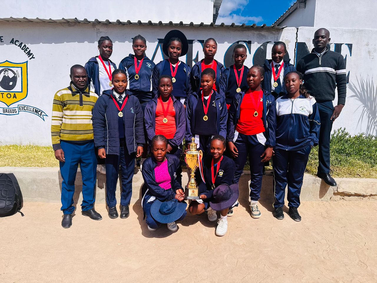 Twin One Academy sports team wearing medals with a trophy